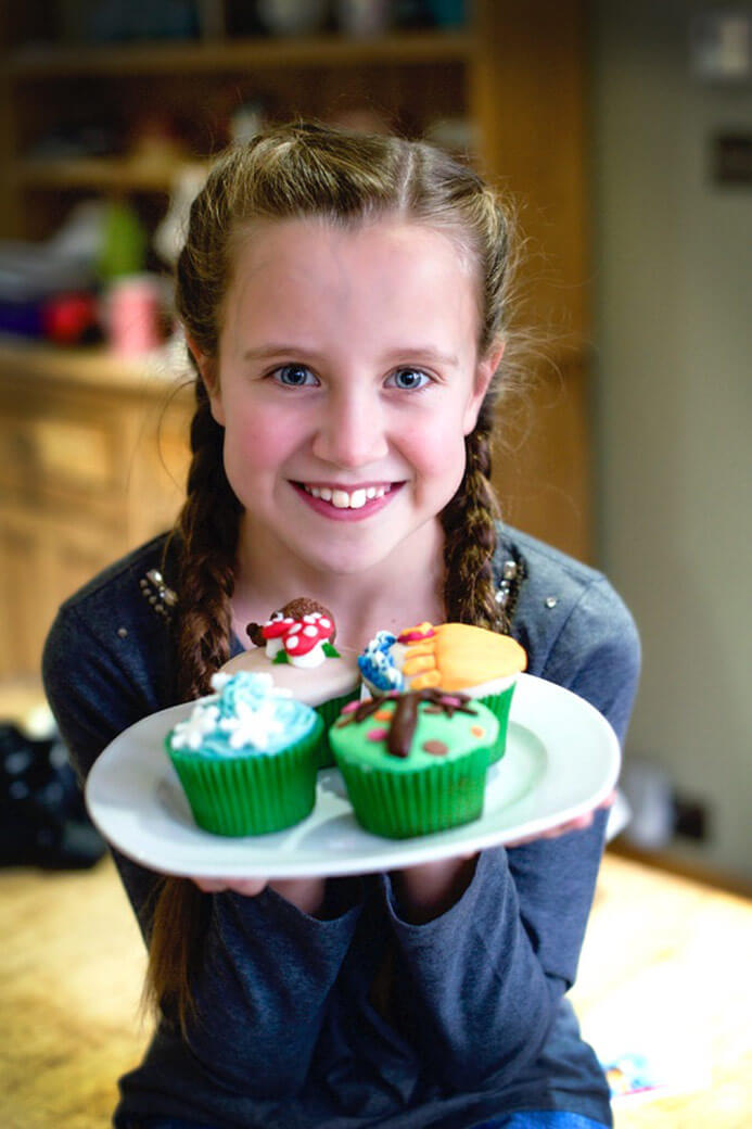 Young girl showing homemade decorated cupcakes